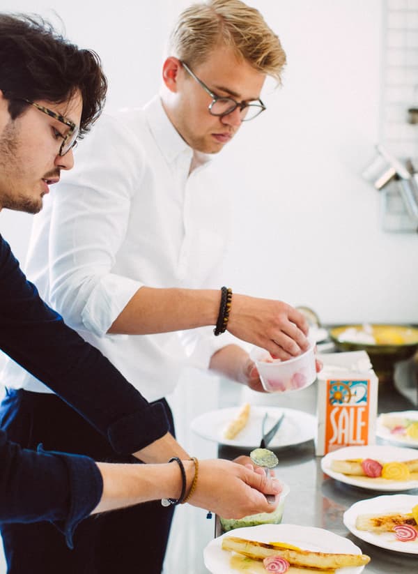 Two young men plating up dishes as part of a “matlag” or food club.