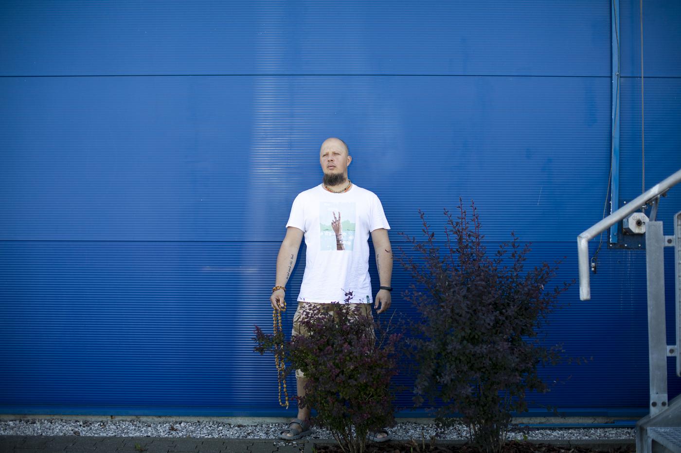 Uchodźca z Białorusi Andrei, stoi na tle niebieskiej ściany i patrzy w stronę kamery