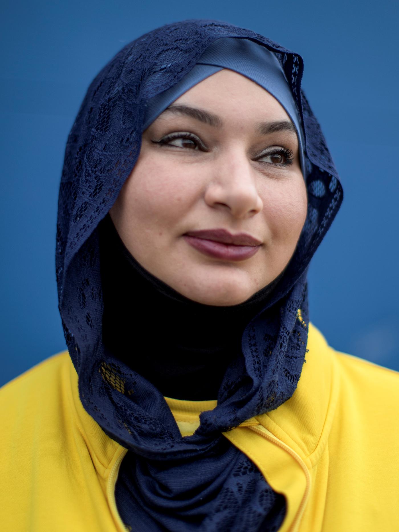 Uchodźczyni z Czeczenii Aza jest śmiechnięta, ma na sobie żółtą bluzę i granatową chistę na głowie. Kobieta patrzy w bok