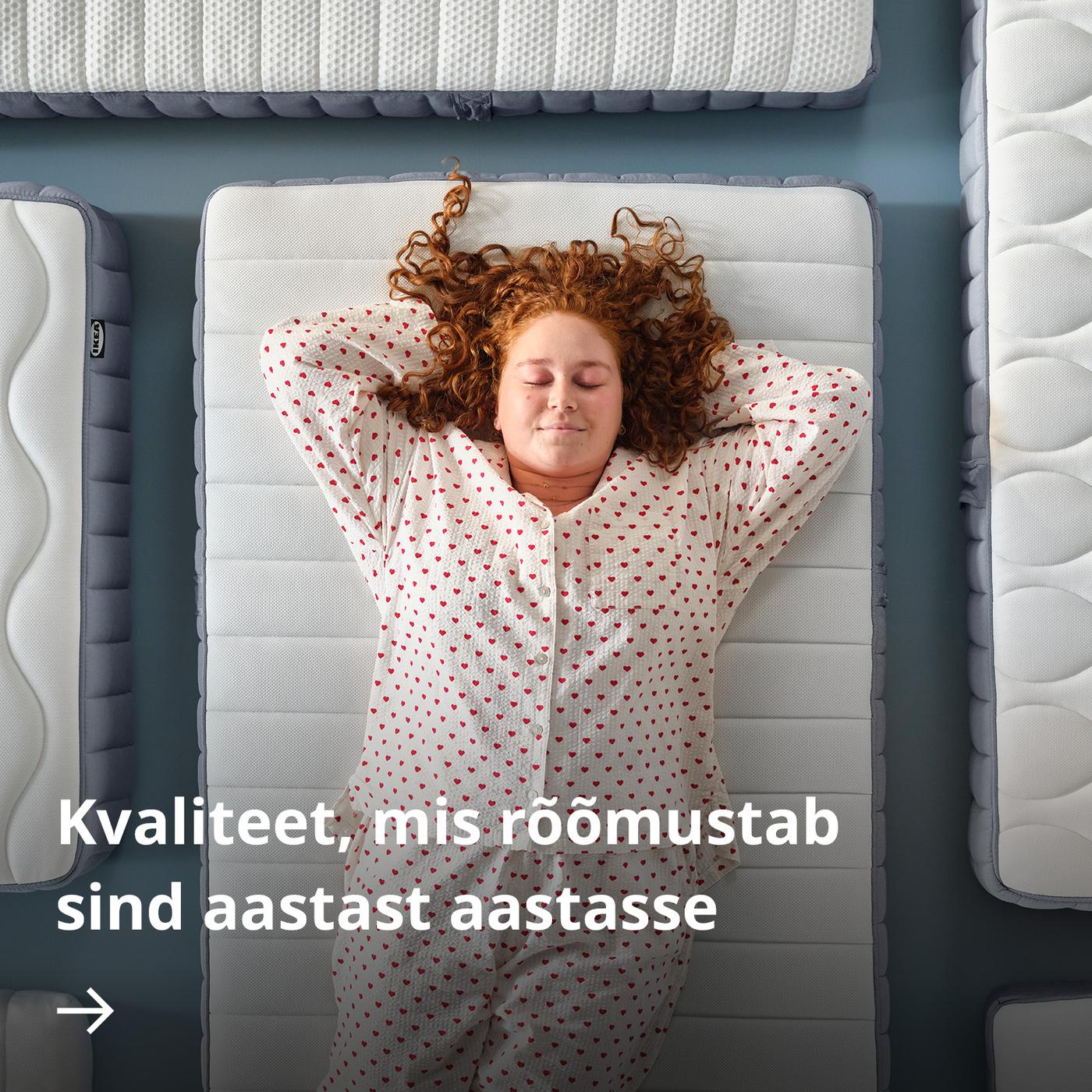Ülaltvaade valges punasetäpilises pidžaamas inimesele, kes lamab madratsil, käed kukla taga. Teda ümbritsevad teised madratsid.