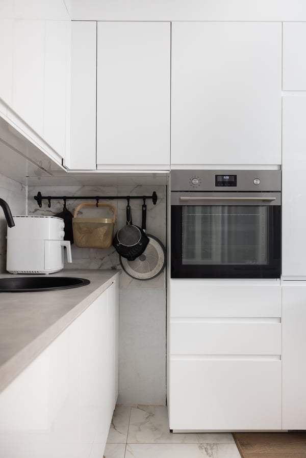Уголок кухни с высокими шкафами и встроенной духовкой; закрытые шкафы и аккуратная столешница.