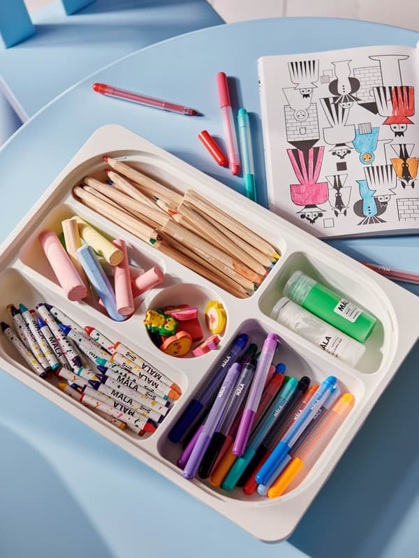 Úložný podnos s priehradkami TROFAST plný výtvarných potrieb MÅLA na svetlomodrom stole MAMMUT.