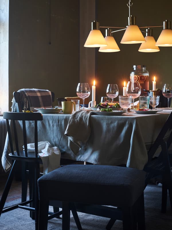 Um candeeiro de teto sobre uma mesa pronta para uma refeição informal. Um banco preto oferece um assento extra.