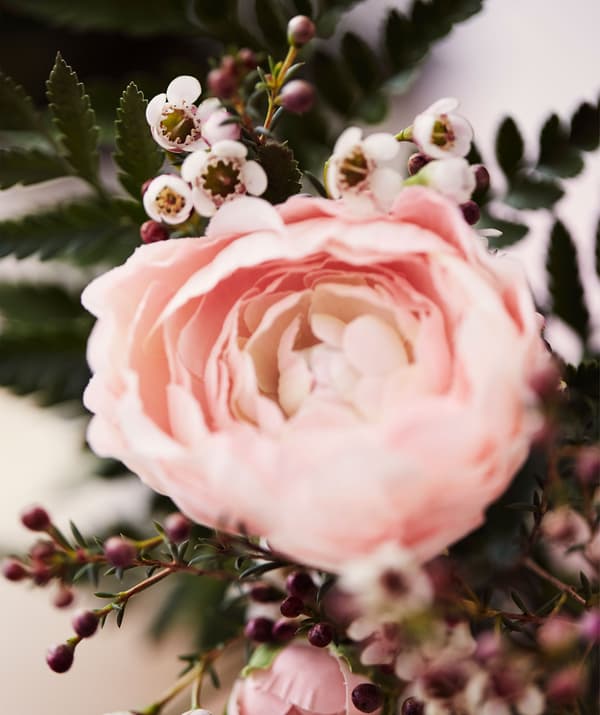 Um pé de ranúnculo artificial cor de rosa com folhagem.