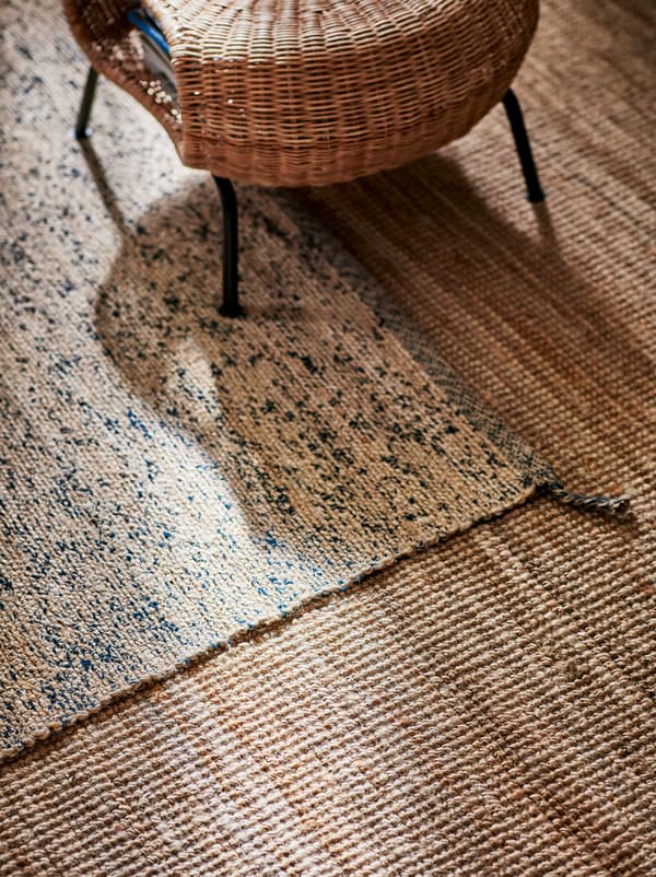 Um repousa-pés GAMLEHULT, em rota entrançada, em cima de um tapete MELHOLT de juta bege, que, por sua vez, está em cima de outro tapete em castanho claro.
