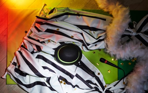 Um varão para cortina de duche BOTAREN que foi transformado numa cortina de palco decorada, disposta no chão, no meio de acessórios de espetáculo.