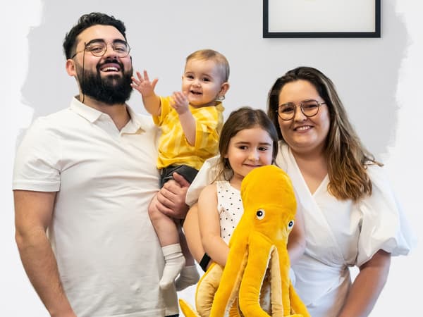 Uma família de quatro a sorrir para uma fotografia.