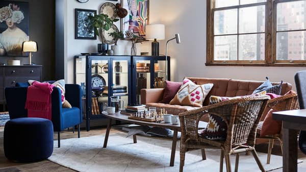 Uma sala com poltronas e um sofá LANDSKRONA em torno de uma mesa de centro, com uma vitrina à esquerda do sofá.