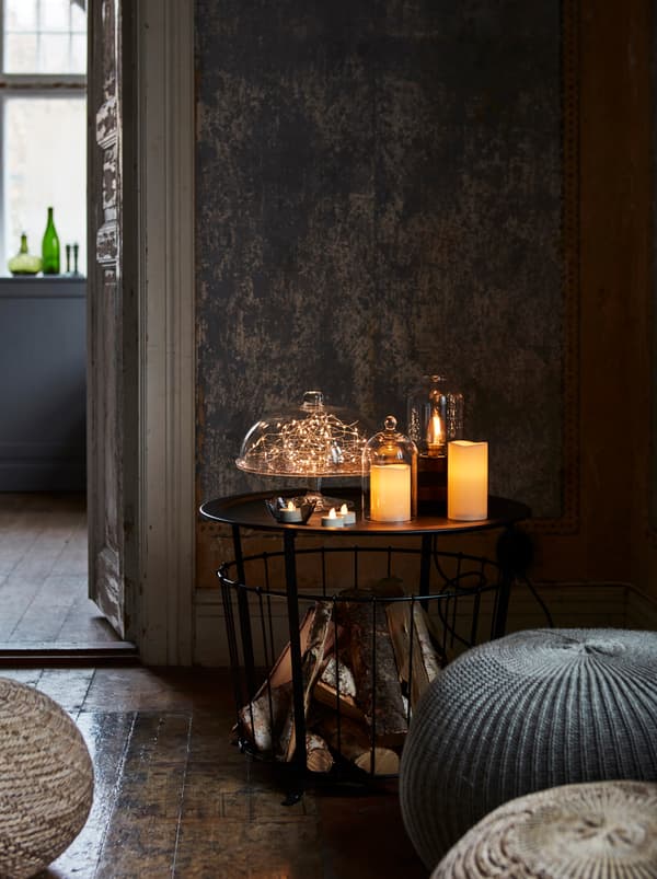 Uma solução de iluminação LED, com velas grandes e pequenas e um sistema de iluminação dentro de campânulas de vidro, ilumina um canto da sala.