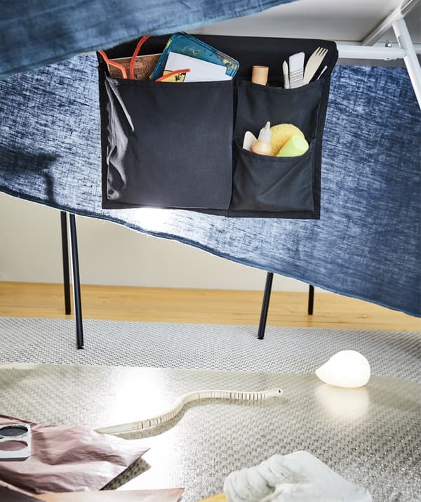 Umjetnički pribor u džepu za krevet ispod blagovaonskog stola, dok tkanina koja visi predstavlja privremeni ministudio.