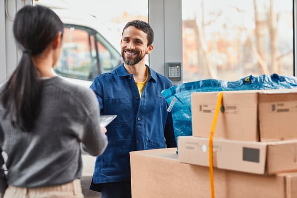 Un addetto alle consegne IKEA consegna a una cliente il suo ordine IKEA da diversi pacchi.