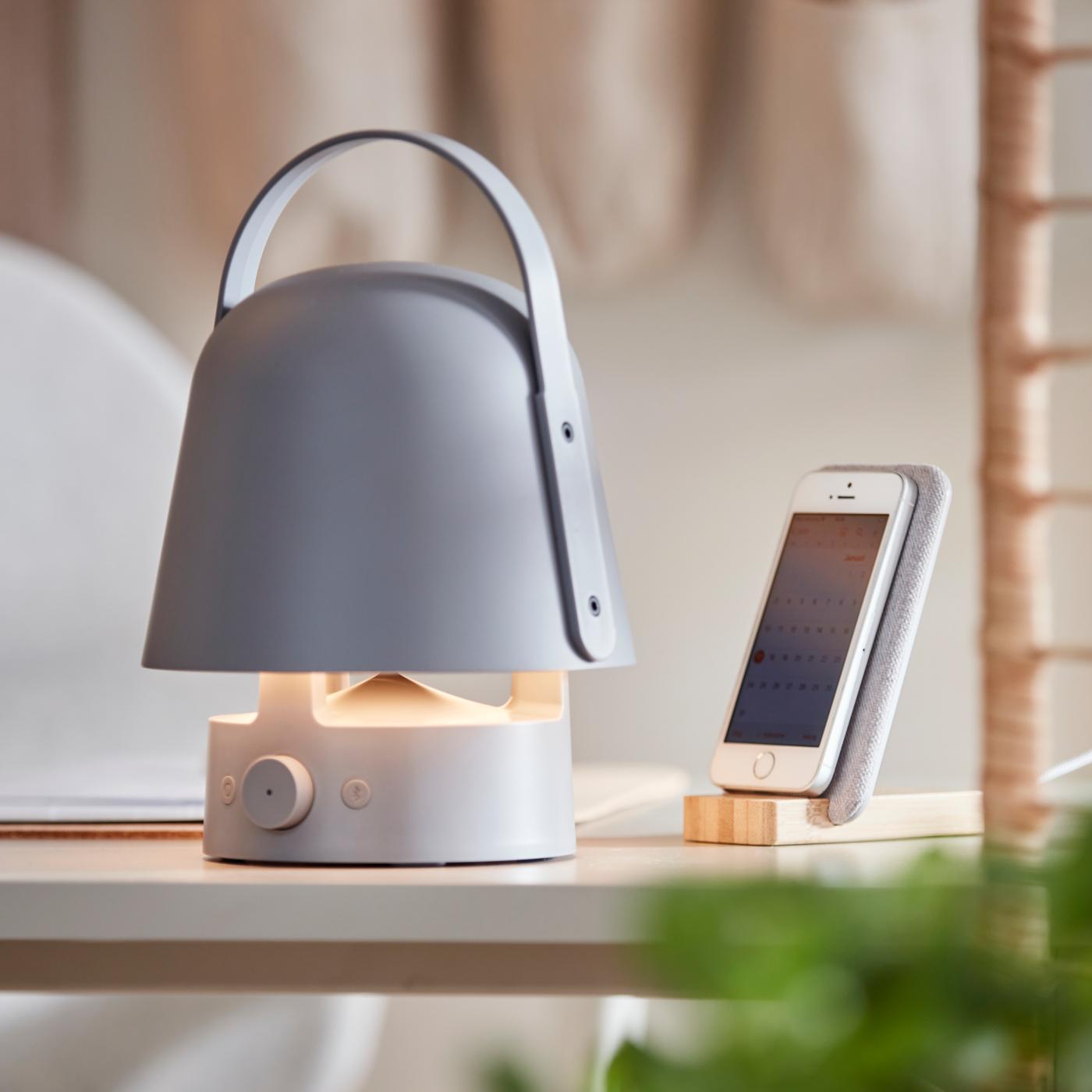 Un altavoz portatil de la serie VAPPEBY sobre una mesa y un movil al lado