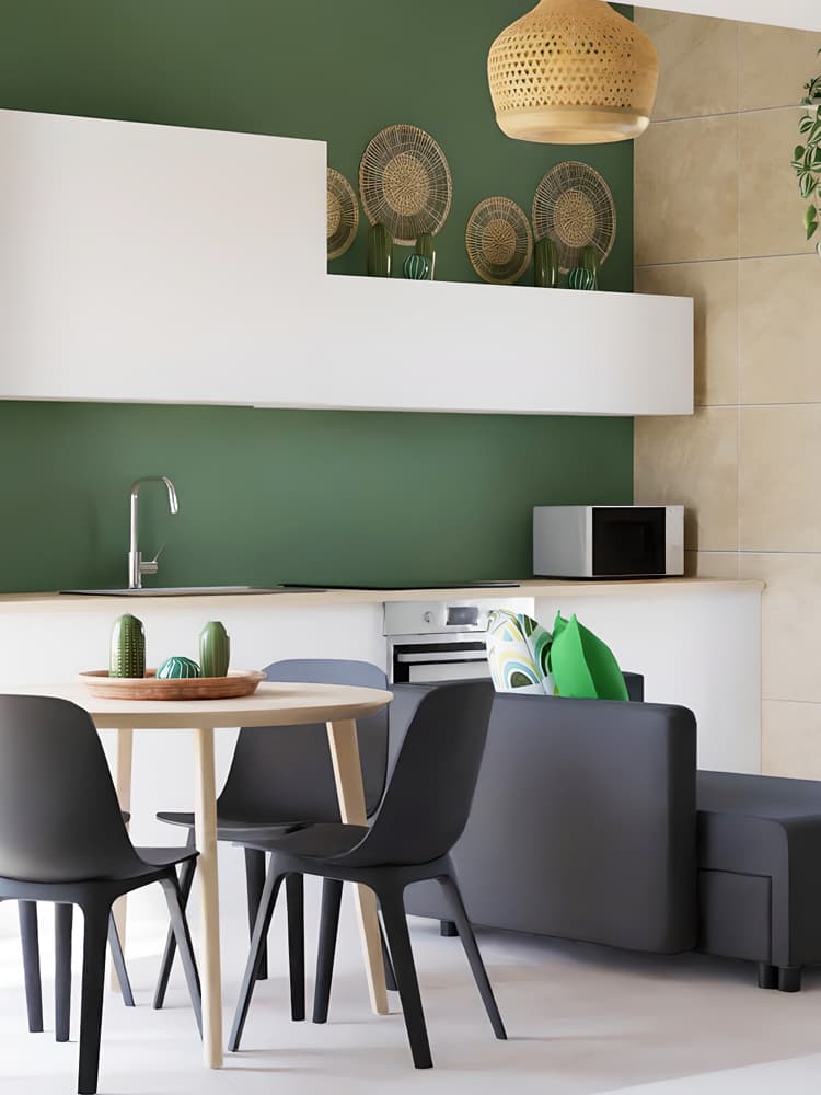 Un ambiente con un divano grigio, delle sedie ODGER, un tavolo tondo in legno chiaro LISABO con al di sopra decorazioni in ceramica SJÄLSLIGT. Sullo sfondo, una parete verde con decorazioni a parete GILLSTAD, alcuni pensili bianchi di una cucina con elettrodomestici. 