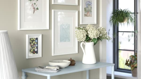 Un ambiente di ingresso sui toni chiari del bianco e dell'azzurro. Una parte con cornici e immagini.