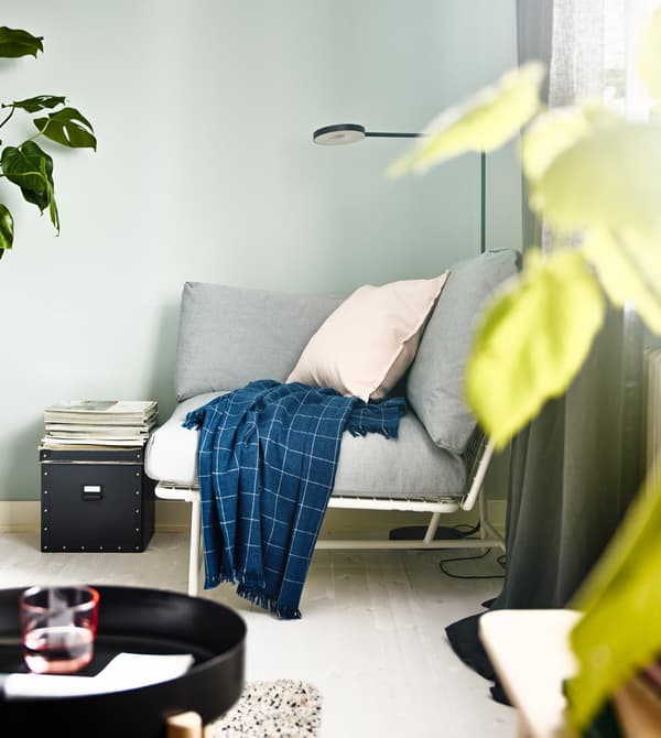 Un angolo arredato per la lettura, con una poltrona angolare con cuscini IKEA PS 2017 e una lampada da terra. 