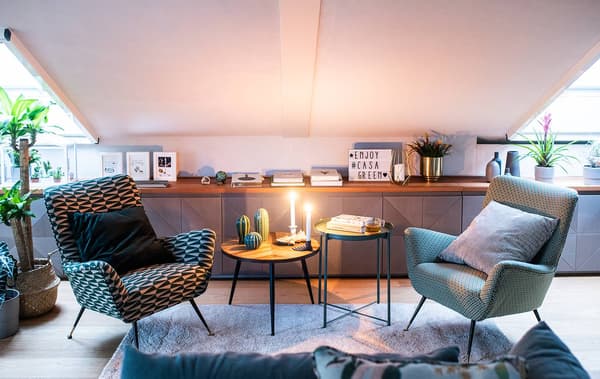 Un angolo del soggiorno con poltroncine vintage e diversi oggetti di decorazione vecchi e nuovi appoggiati sul piano. Tavolino, tappeto e lampada IKEA.