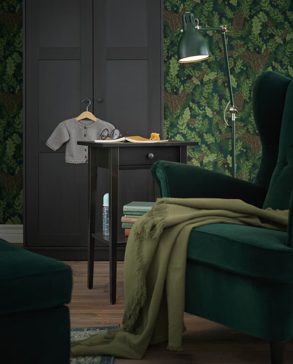 Un angolo lettura con una poltrona verde, una lampada da terra verde e un comodino HEMNES usato come tavolino - IKEA