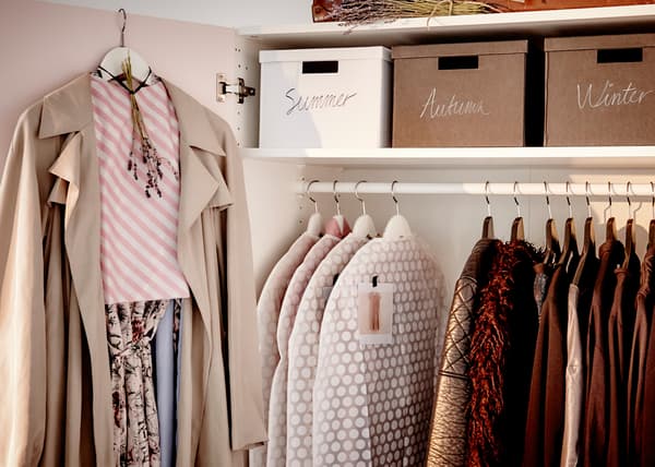 Un armadio aperto con all'interno alcuni indumenti appesi e scatole. Un look completo è appeso con una gruccia ad un'anta.