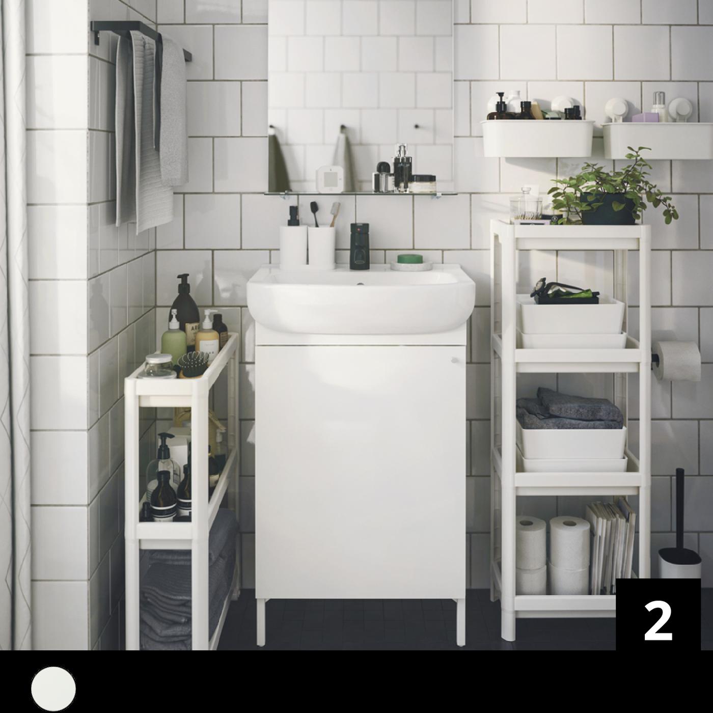 Un bagno bianco con mobili a colonna e accessori per la toilette.