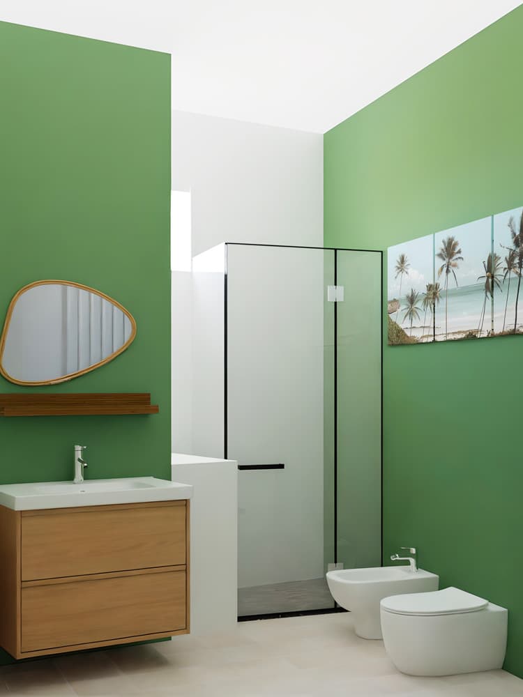 Un bagno con pareti verdi, un mobile con lavabo e cassetti e uno specchio MARISTOVA. C'è una nicchia con una doccia con profili neri e alla parete c'è una stampa tropicale.