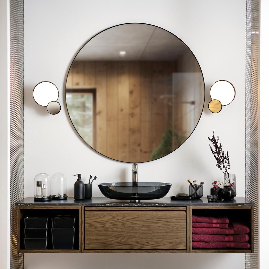 Un bagnoÄNGSJÖN marrone effetto rovere visto frontalmente completo di lavabo da appoggio vetro/grigio scuro, mobile per lavabo con un cassetto e due vani portasciugamani, specchio rotondo molto grande con a finaco due illuminazioni rotonde.