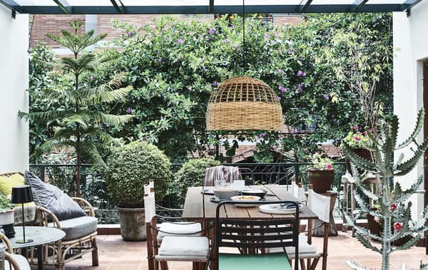 Un balcon avec des plantes, des chaises et une suspension.