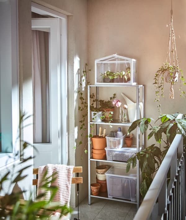 Un balcón dun apartamento urbano cheo de plantas. Os testos do chan, da parede e da guía crean un oasis.