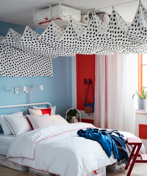 Un baldacchino realizzato con tessuto a metraggio SKÄGGÖRT appeso a due fili per tende nasconde dei bastoni appendiabiti MULIG fissati al soffitto - IKEA