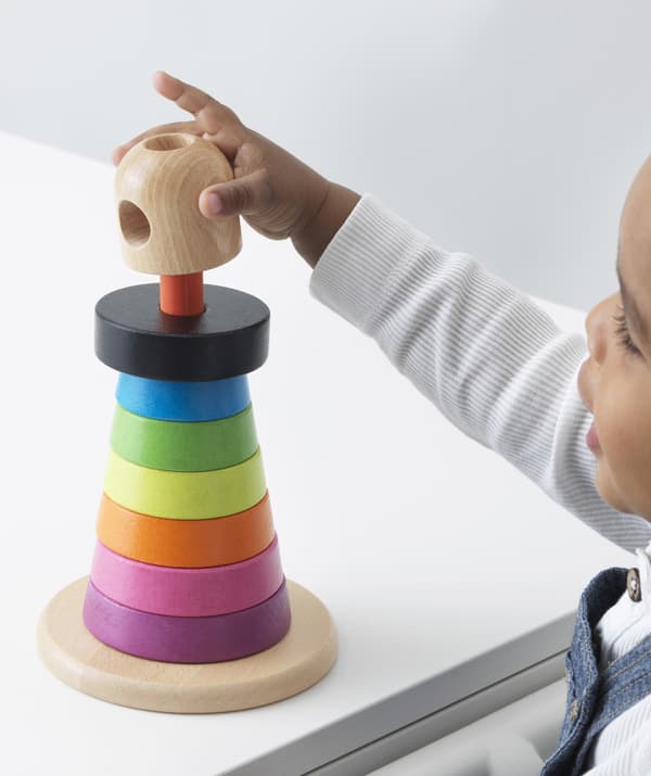 Un bambino gioca con una piramide ad anelli colorati.