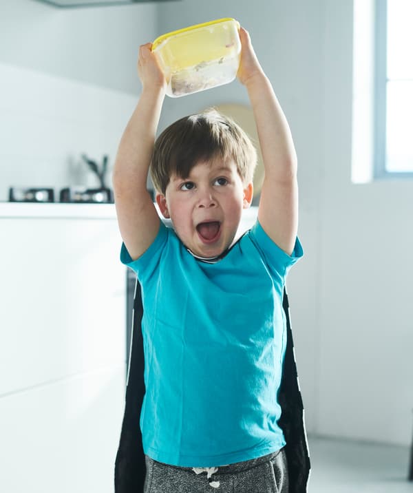 Un bambino si diverte a sbucciare l'aglio scuotendo un contenitore di plastica. 