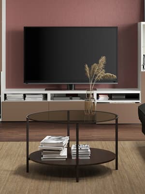 Un banc TV BESTA devant une table basse ronde noire.