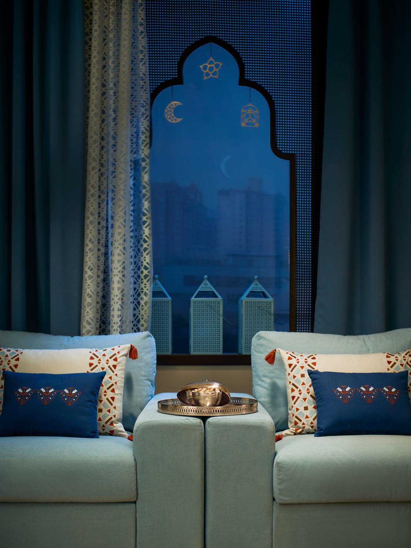 Un bol GOKVÄLLÅ sobre una bandeja GOKVÄLLÅ, situada sobre los reposabrazos de dos sofás azules colocados uno junto al uno al otro y adornados con cojines GOKVÄLLÅ.