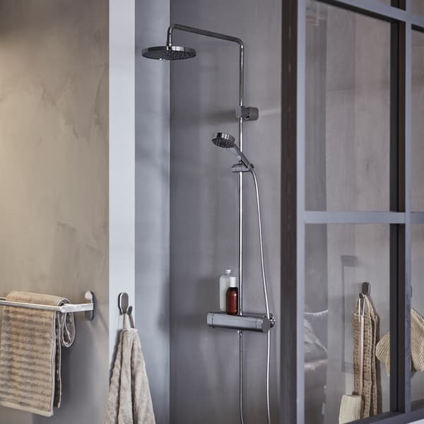 Un box doccia grigio con soffione e doccetta, con asciugamani beige appesi a dei ganci.