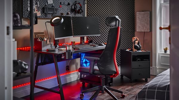 Un bureau gamer UTESPELARE noir avec deux écrans, un fauteuil gamer noir, un caisson à tiroirs noir et divers accessoires de gaming.