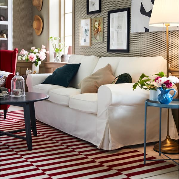 Un canapé EKTORP à trois places blanc sur un tapis blanc et rouge dans une salle de séjour au look traditionnel.