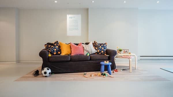Un canapé EKTORP de présentation se trouve à côté de coussins et d’objets comme un ballon de soccer, un ensemble de train pour enfants et des tables gigognes.