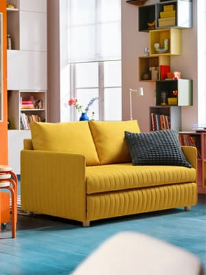 Un canapé FRIDHULT jaune dans un salon.