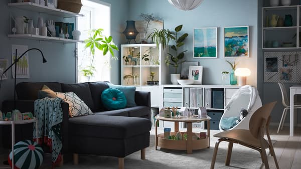 Un canapé trois places avec méridienne, une étagère avec portes, un fauteuil pivotant, une table basse et des jouets.