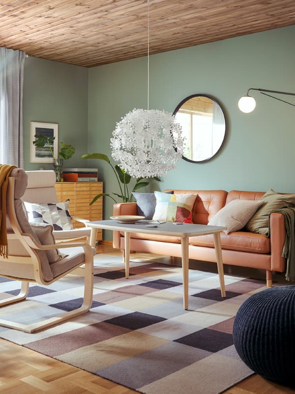 Un canapé, une console et deux fauteuils POÄNG, un brun clair et un blanc, à la structure flexible en bois clair.