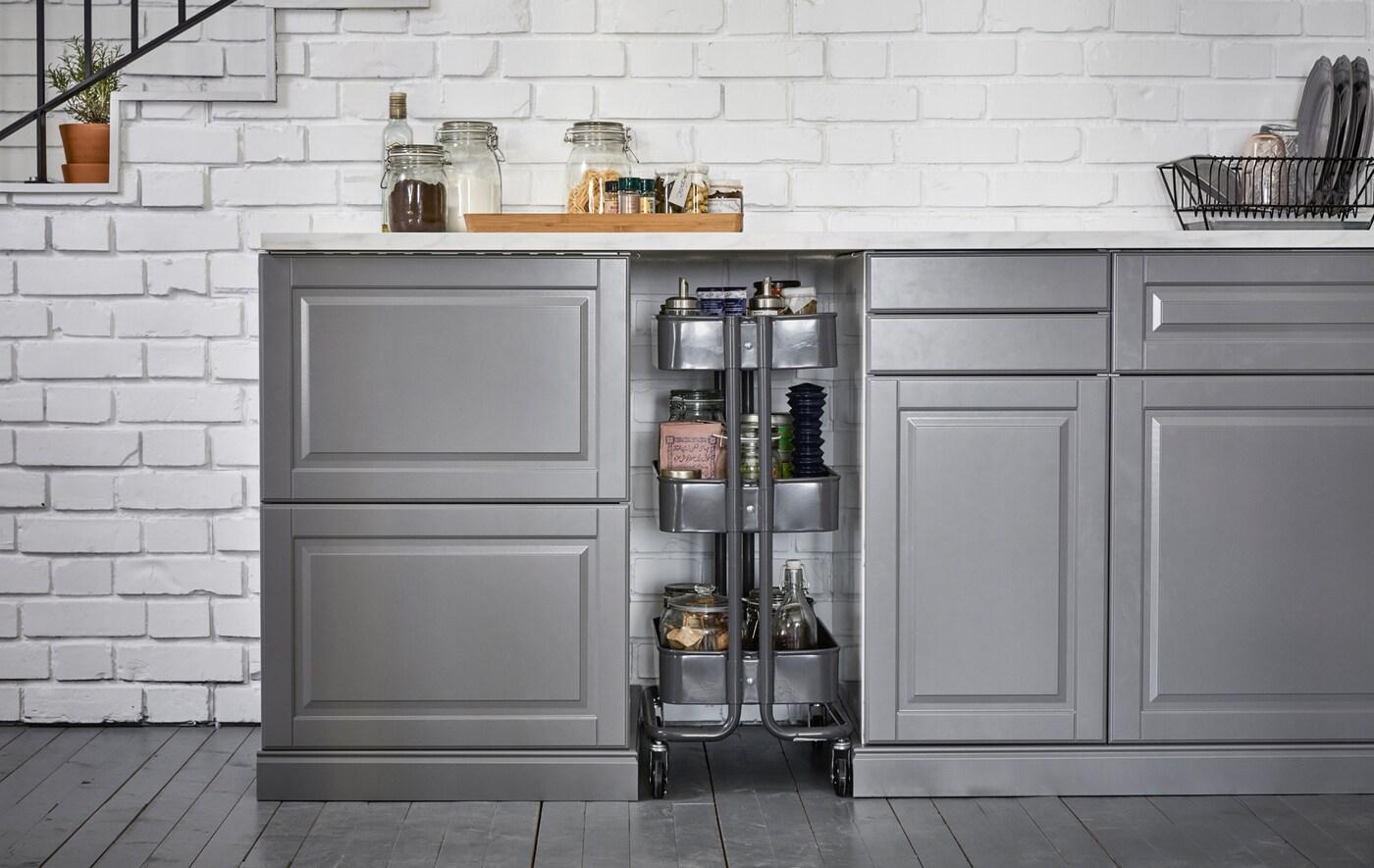 Un carrito de cocina con ruedas dentro de un hueco entre los muebles para aprovechar el espacio