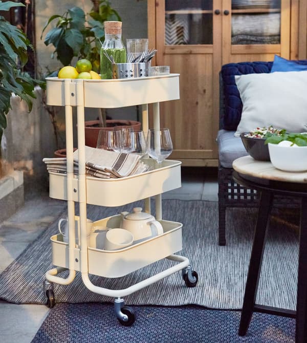 Un carrito de cocina RÅSKOG guarda un juego de té y vajilla en un salón.