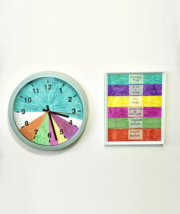 Un ceas de perete împărțit în segmente colorate lângă o legendă cu coduri de culoare pentru activitățile de familie.