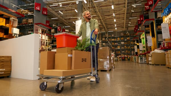 Un cliente con un carro con paqeutes planos de sus compras en IKEA.