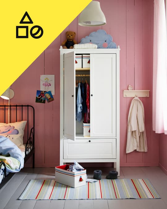 Un clóset infantil independiente con una puerta abierta mostrando las prendas colgadas en el interior.