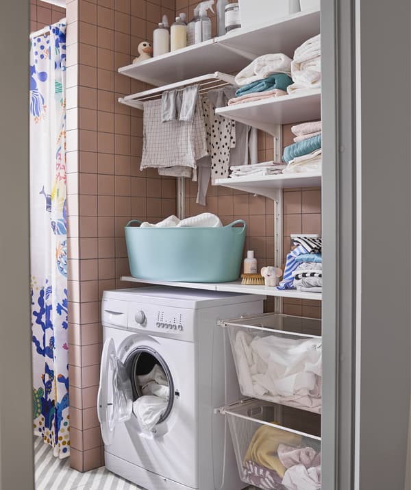 Un coin buanderie avec lave-linge, étagères et paniers à linge.