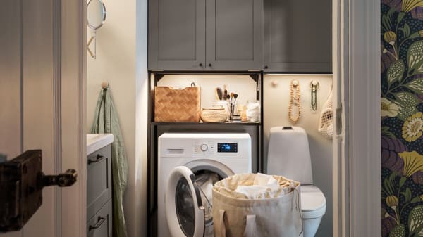 Un coin buanderie dans une salle de bain: élément avec faces ENHET en gris, un combi lave-linge/sèche-linge UDDARP et un sac à linge PURRPINGLA.