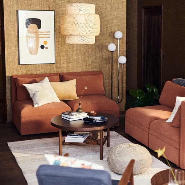 Un coin salon avec des canapés, une lampe, un abat-jour suspendu et une table basse.
