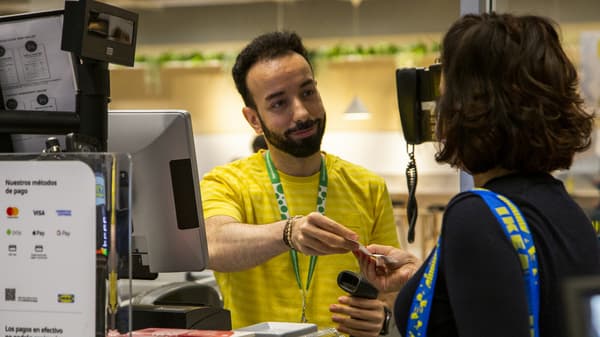 Un col·laborador d'IKEA resol una consulta d'una clienta a un mostrador del servei d'atenció al client d'IKEA.
