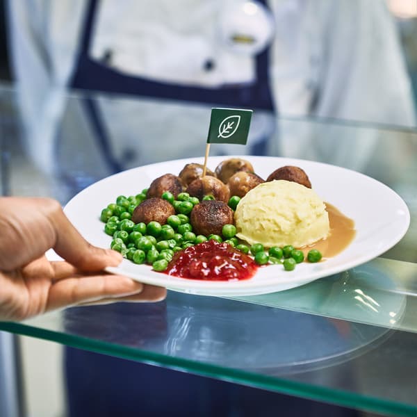 Un collaborateur du restaurant IKEA remet un repas de boulettes de viande à un client.