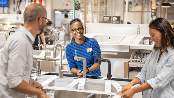 Un collaborateur en chemise bleue aide deux clients dans un magasin IKEA.